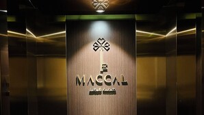 Interior de elevador com painel de madeira e logotipo do hotel "MACCAL hotel dalat".