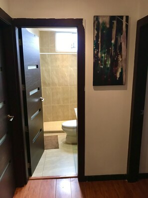 Kylpyhuone, jossa on wc, suihkutila ja laatoitettu lattia.