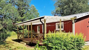 A red building with a wooden deck and a covered porch. - 5 Person Holiday Home in Billingfors (Billingsfors)
