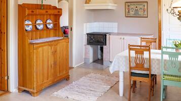 A kitchen with wooden cabinetry, a stove, and a dining area with a table and chairs.