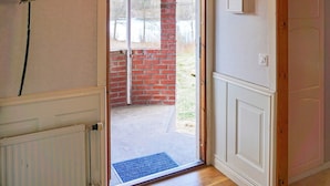 A doorway leading to a balcony with a brick wall and a white door with a light switch. - 5 Person Holiday Home in Billingfors (Billingsfors)