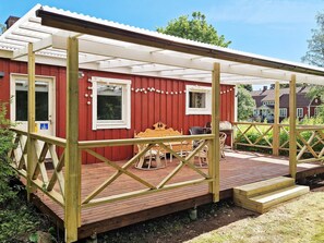 A red wooden building with a covered patio area, a wooden table, and chairs. - 5 Person Holiday Home in Billingfors (Billingsfors)