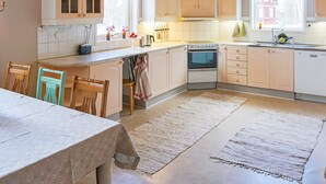Une cuisine avec des meubles de rangement en bois, une cuisinière et un coin repas comprenant une table et des chaises.