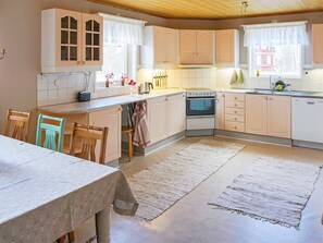 Une cuisine avec des meubles de rangement en bois, une cuisinière et un coin repas comprenant une table et des chaises.