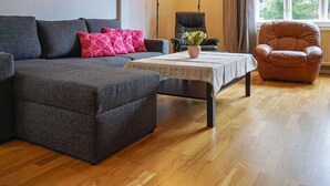 Un salon comprenant un canapé, une table basse, un fauteuil et une lampe.