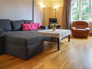 Un salon comprenant un canapé, une table basse, un fauteuil et une lampe.
