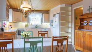 A traditional kitchen with wooden cabinets, a dining table with chairs, and a chandelier. - 5 Person Holiday Home in Billingfors (Billingsfors)