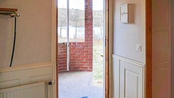 A room with a door leading to a balcony, a radiator, and a white cabinet with a nameplate.