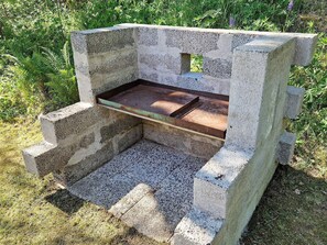 A concrete bench with a metal tray, surrounded by grass and plants. - 5 Person Holiday Home in Billingfors (Billingsfors)