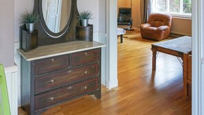 Une pièce comprenant une commode en bois, un miroir, une table et une chaise.