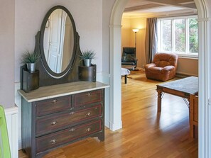 Une pièce comprenant une commode en bois, un miroir, une table et une chaise.
