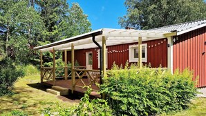 A red building with a covered porch and a wooden deck. - 5 Person Holiday Home in Billingfors (Billingsfors)