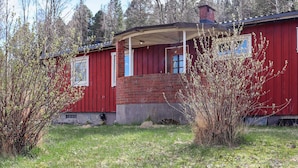 A red wooden house with a brick chimney, a covered porch, and a small front yard. - 5 Person Holiday Home in Billingfors (Billingsfors)
