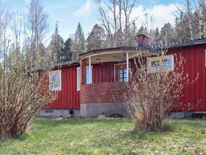 Et rødt træhus med skorsten i mursten, en overdækket veranda og en lille forhave.