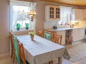 A dining area with a table set for four, a chandelier, and a view of the kitchen. - 5 Person Holiday Home in Billingfors (Billingsfors)