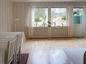 A room with a bed, a desk with two lamps, a radiator, and a window with curtains. - 4 Star Holiday Home in Ekero (Ekerö)