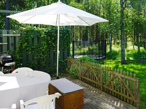 A wooden deck with a white umbrella, a barbecue grill, and a trampoline. - 4 Star Holiday Home in Ekero (Ekerö)