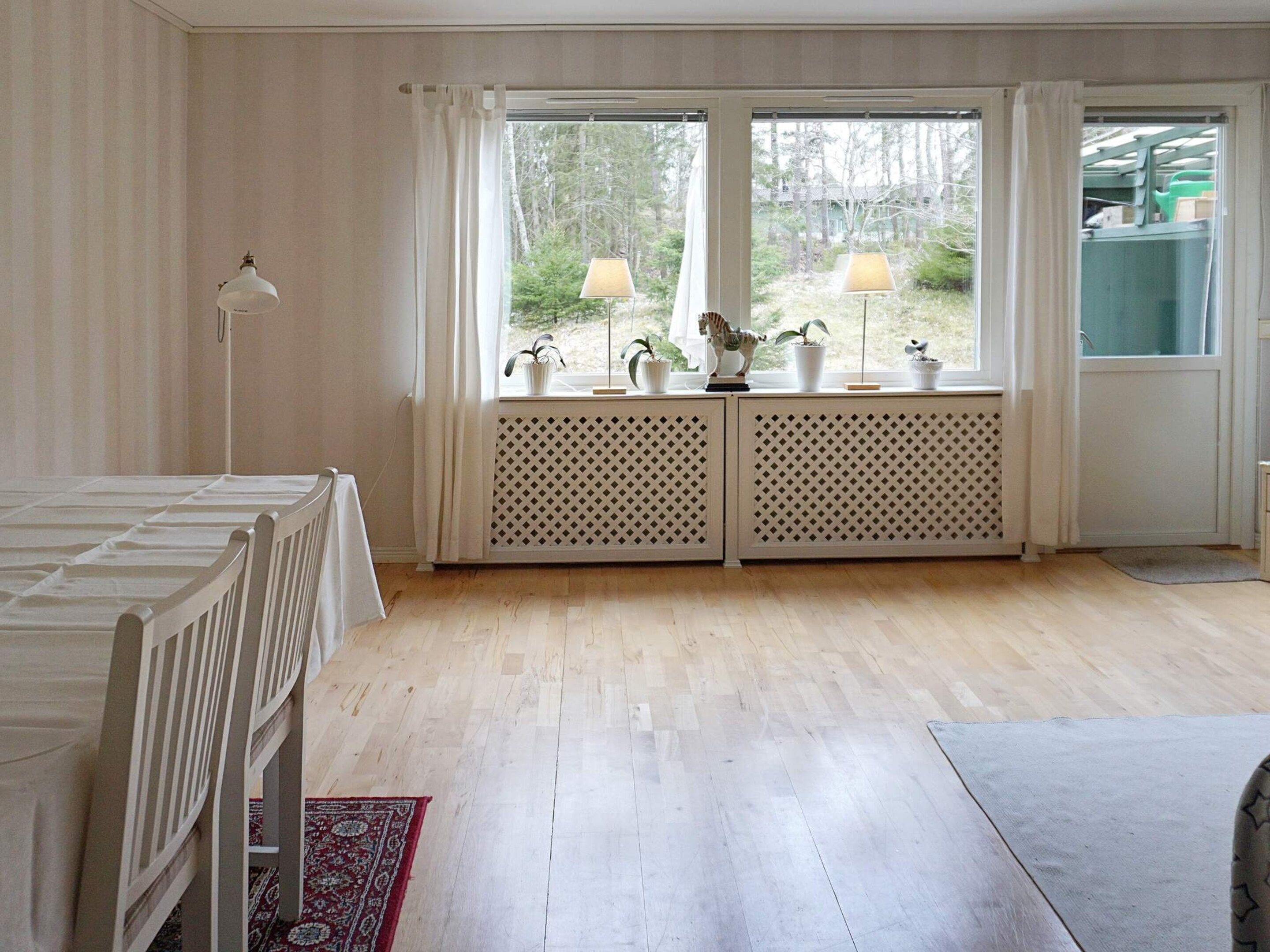 Une pièce avec un lit, une fenêtre avec des rideaux, un radiateur et une lampe.