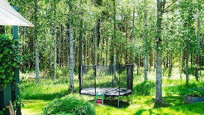 Een trampoline in een bebost gebied, met een groene constructie in de buurt.