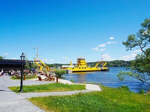 A waterfront area with a yellow boat docked, a paved walkway, and a small park with benches. - 4 Star Holiday Home in Ekero (Ekerö)