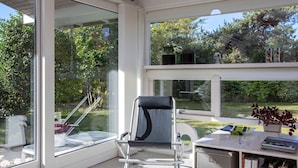Une chambre moderne avec de grandes fenêtres, un bureau avec des livres et une chaise.