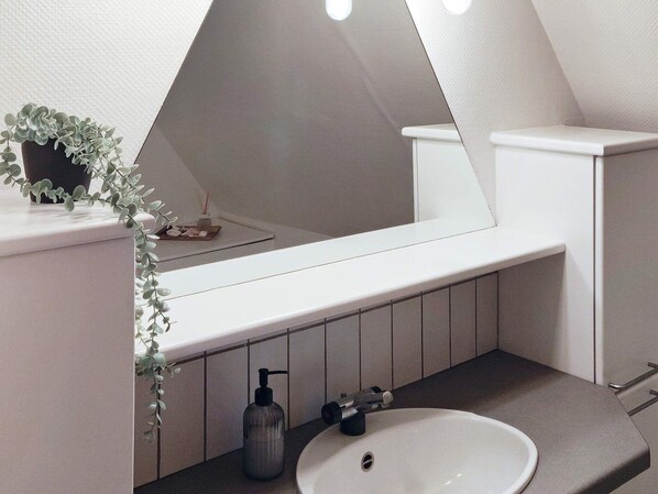 A modern bathroom with a white sink, a large mirror, and a small potted plant on the countertop. - 8 Person Holiday Home in Hojer (Højer)