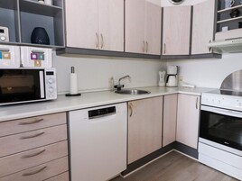 Una cocina moderna con armarios blancos, microondas, cafetera y lavavajillas.