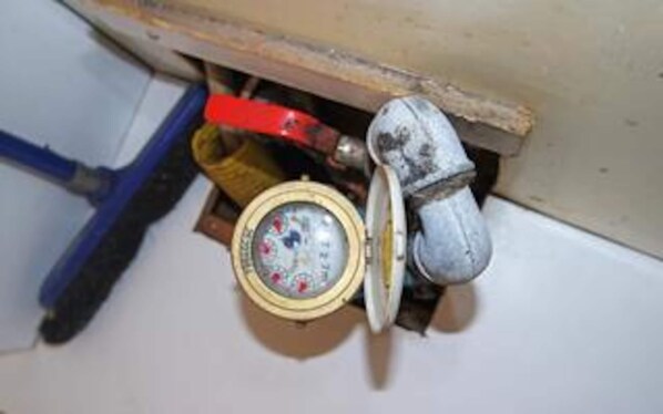 A toilet with a visible water level indicator, a metal pipe, and a red tool. - 6 Person Holiday Home in Hadsund (Hadsund)