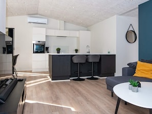 A modern kitchen with white cabinets, a central island, and two bar stools.