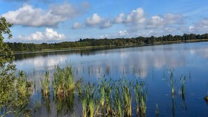 Un lac paisible où se reflètent le ciel et les arbres environnants.