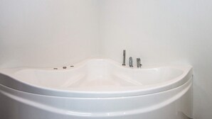 Une baignoire blanche au design incurvé, dotée d’un seul robinet et d’une molette de réglage.