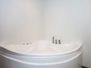 A white bathtub with a curved design, a single faucet, and a control knob. - 5 Star Holiday Home in Ansager (Ansager)