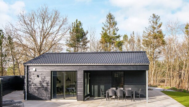 Une maison moderne dotée d’un patio, de grandes fenêtres et d’un coin repas.