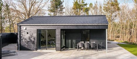 A modern house with a patio, large windows, and a dining area.