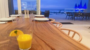 A dining table with chairs, salt and pepper shakers, and a glass of orange juice. - Mexico,Oceanfront vacation villa,Lighthouse Point, near Costa Palmas, private (La Ribera)