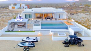 A modern resort with a pool, lounge area, and multiple vehicles including a jet ski and ATV. - Mexico,Oceanfront vacation villa,Lighthouse Point, near Costa Palmas, private (La Ribera)
