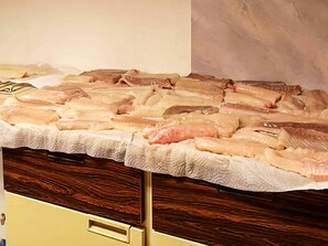 Pescado crudo exhibido sobre una barra de madera.