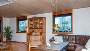 A cozy living room with a wooden ceiling, a leather sofa, a wooden coffee table, and a built-in wooden cabinet with shelves. - 8 Person Holiday Home in Kolind (Kolind)