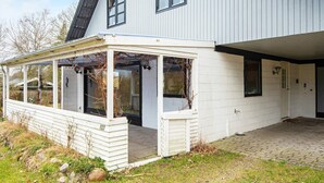 A modern house with a covered porch, a brick driveway, and a number 103 on the porch. - 8 Person Holiday Home in Kolind (Kolind)