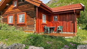 A wooden cabin with a red roof, two windows, and a small porch with green chairs. - 5 Person Holiday Home in Hemsedal (Hemsedal)