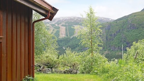 A wooden cabin with a sloped roof, surrounded by lush greenery and a mountainous landscape. - 5 Person Holiday Home in Hemsedal (Hemsedal)