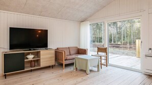 A modern living room with a flat-screen TV, a sofa, a table, and a chair. - 9 Person Holiday Home in Laeso (Læsø)