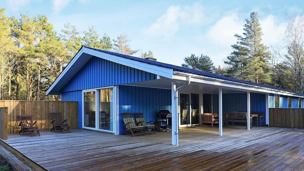 A blue metal building with a covered patio area, wooden deck, and outdoor seating. - 9 Person Holiday Home in Laeso (Læsø)