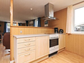 A compact kitchen with wooden cabinets, a stove, and a window. - 6 Person Holiday Home in Lokken (Lokken)