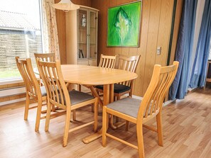 A dining area with a wooden table and chairs, a cabinet with glass doors, and a green abstract painting on the wall. - 6 Person Holiday Home in Lokken (Lokken)