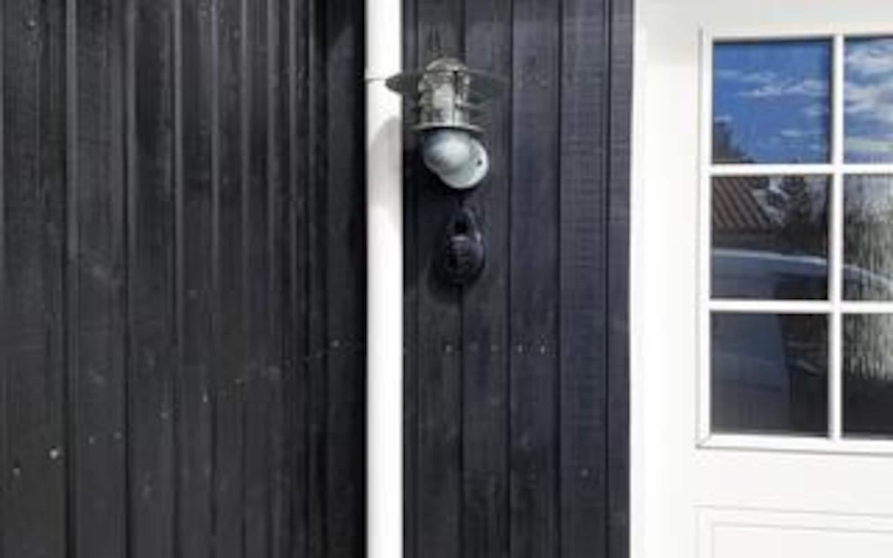 A dark wooden door with a metal doorbell and a window to the right.