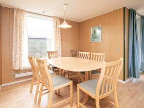 Een eetkamer met een ronde houten tafel en zes stoelen met grijze kussens.