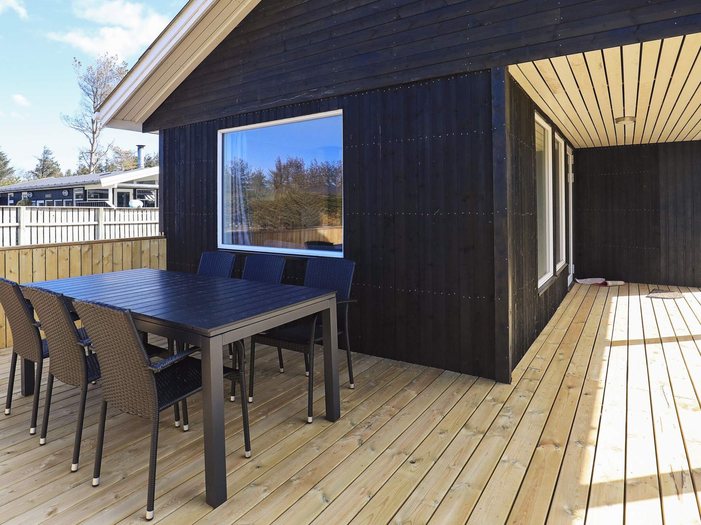 Una terraza con mesa y sillas, un ventanal grande y una cubierta de madera.