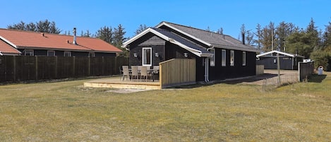 A residential property with a fenced backyard, a patio with outdoor furniture, and a garage.