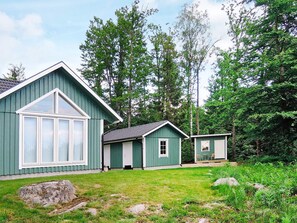 Une maison en bois peinte en vert, dotée d’une grande fenêtre et d’une petite annexe attenante.